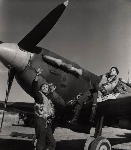 This 1943 photograph shows two West Indian members of the Bombay Squadron which took part in Fighter Command sorties over enemy occupied territory. Flying Officer A O Weekes of Barbados (left) and Flight Sergeant E A Joseph of San Fernando, Trinidad pose with a Spitfire fighter aircraft. Spitfires were single-seat fighters and first distinguished themselves in the Battle of Britain in summer 1940.